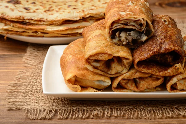 Crepes stuffed with chicken and mushrooms on wooden table. — Stock Photo, Image