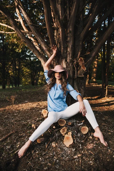 Kvinna som bär hatt sitter i skogen — Stockfoto