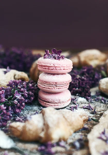 Pastry and macaroons with lilac flowers on table — Stock Photo, Image