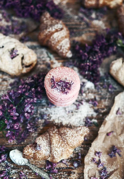Pastry and macaroons with lilac flowers on table — Stock Photo, Image