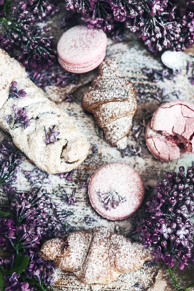 Pastry and macaroons with lilac flowers on table — Stock Photo, Image