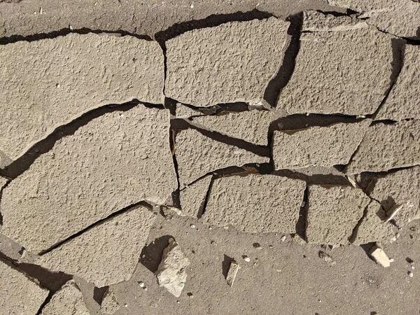 Трещины в бетоне. Асфальт разбит на куски. Поверхность треснула. Текстура. Стоковое Изображение