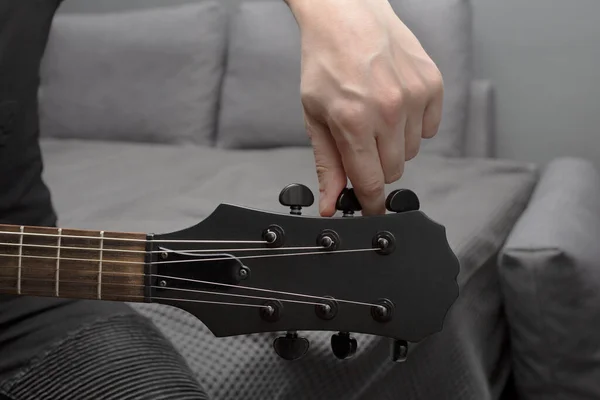 Siyah elektro gitar akordu. Parmaklar akort mandalını çeviriyor. Çerçeveyi ver. Gitar çalmayı öğreniyorum..