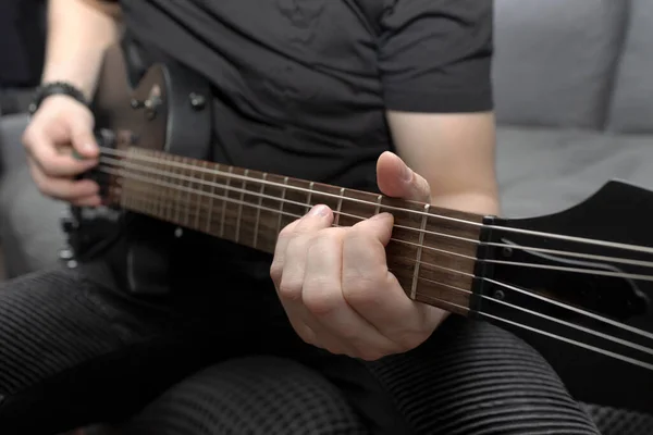 Siyah elektro gitar çalan bir müzisyen. Gitar fretboard 'u yakın plan. Gitar çalmayı öğreniyorum. Evde kişisel gelişim