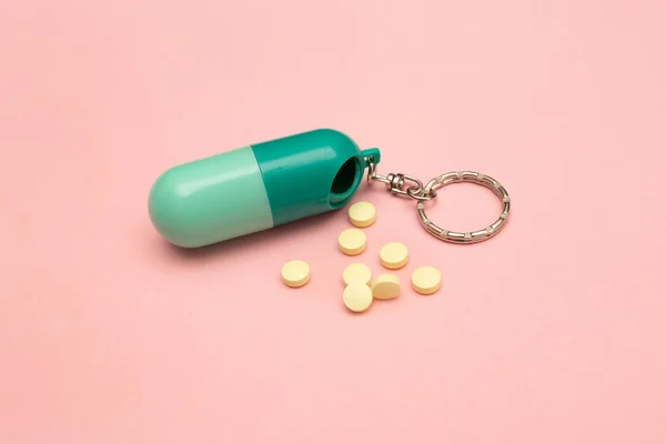 Caixa de pílulas de viagem. Forma de comprimido. Utilização de comprimidos em doses. Mantém a saúde. Muitas pílulas amarelas em um fundo rosa. — Fotografia de Stock