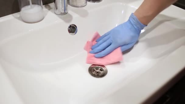 Junger Mann wäscht eine schmutzige Spüle. Hände in Schutzhandschuhen. Reinigung des Badezimmers. Hausreinigungskonzept. Wischt die Spüle ab — Stockvideo