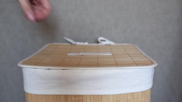 O homem põe roupa suja numa cesta de roupa feita de bambu. Trabalho doméstico. Rotinas domésticas. — Vídeo de Stock