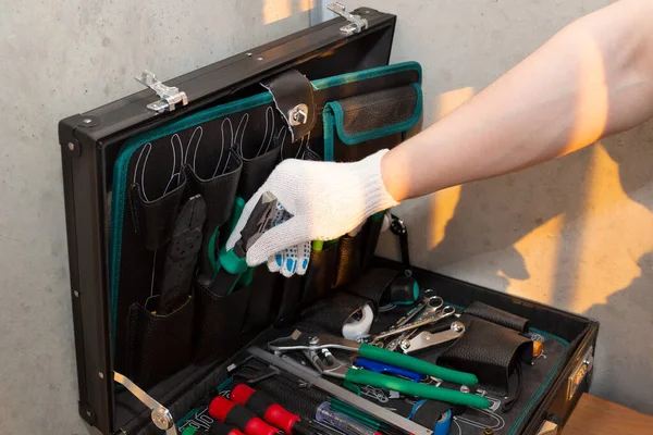 Man takes the tool from the toolbox. Tools for repair. The mechanic takes the pliers. A set of tools in a square box.