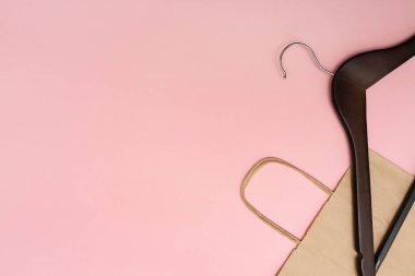 Pembe arka planda ahşap elbise askısı. Saplı bir kese kağıdı. Uzayı kopyala Mesaj için yer. Alışveriş konsepti. Düz yatıyordu.