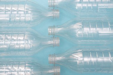  Mavi arka planda boş kullanılmış plastik şişeler. Plastik geri dönüşüm sorunu. Plastik üretim ve işleme kavramı.