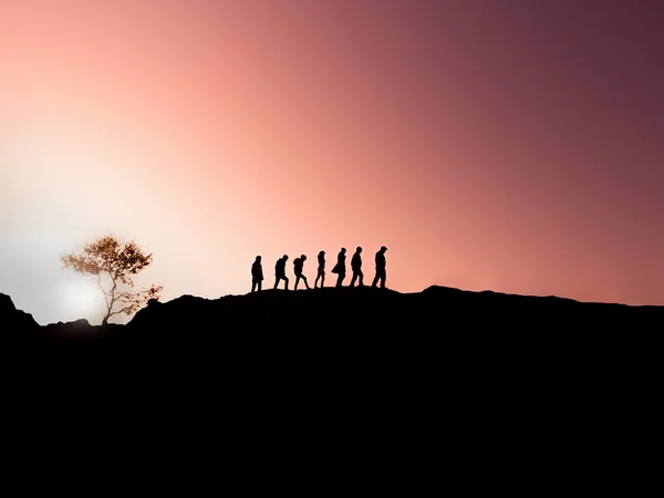 Siluetas de una familia de caminatas al atardecer . — Foto de Stock