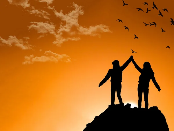 Amigos en la cima de una montaña sacudiendo manos levantadas — Foto de Stock