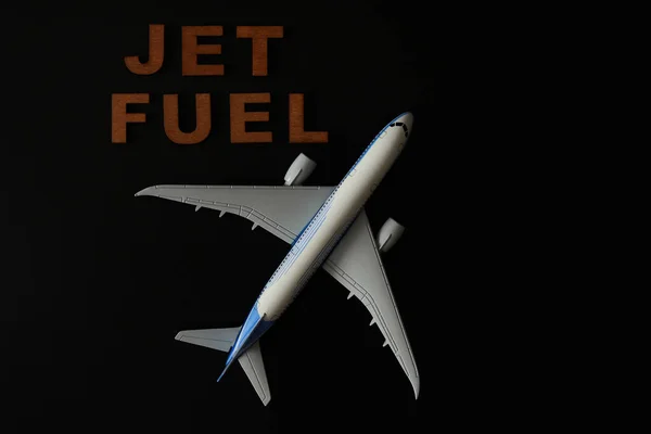 Air-plane model and Jet fuel word abstract in wooden letters. Low-key photo.