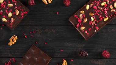 Fıstıklı ahududu ve ahşap kaplama cevizli doğal koyu siyah çikolata. Sağlıklı diyet yemekleri. Fotoğrafın ortasında mesaj için yer. Üst görünüm.