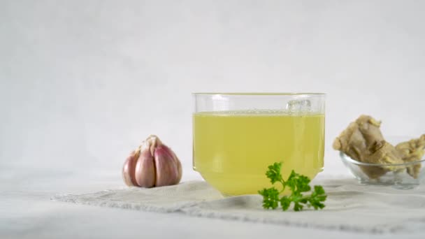 Womans hand puts parsley leaves on the table next to a mug of bone broth. — Stock Video