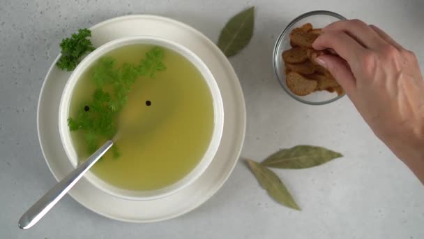 Weibliche Hand gibt Paniermehl oder Croutons in die Knochenbrühe. — Stockvideo