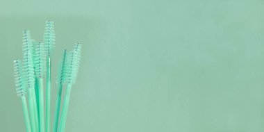 Arka planda naneli makyajlı kaş fırçası. Kaş ve kirpik tarakları. Kirpikler ve kaşlar için tek kullanımlık pembe fırça. Boşluğu kopyala.