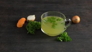Soğan, havuç ve maydanoz yapraklı cam bardakta sağlıklı tavuk kemiği çorbası..