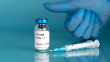 Coronavirus sars-cov-2 aşı geçmişi. Covid-19 aşı şişesi ve korona aşısı için şırınga enjeksiyonu. Doktorlar mavi bir eldiven verdiler. Parmağını kaldırdı..