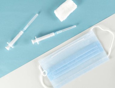 Virüslere karşı koruyucu maskeli aşı şırıngası. Coronavirus Covid-19 aşısı. Mavi ve beyaz arka plan. Üst görünüm.