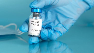 Coronavirus aşı şişesi. Doktorların elinde Covid-19 aşısı için aşı ampulü vardı. Covid 'i durdur. Yüz maskeni çıkar..