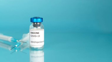 Coronavirus aşı şişesi. Aşı şişesi ve şırıngalarla kapak aşısı. Mavi arka plan. Boşluğu kopyala.