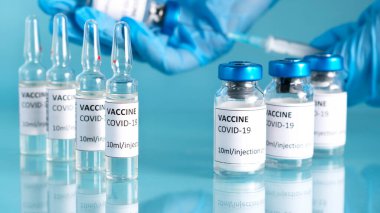 Aşı şişeleri ve ampullerle Coronavirus aşısı. Doktorlar ellerinde Coronavirus tedavisi için şırınga ve aşı şişesi tutuyor. Covid-19 aşısı araştırmacıların elinde. Salgın sırasında klinik deney.