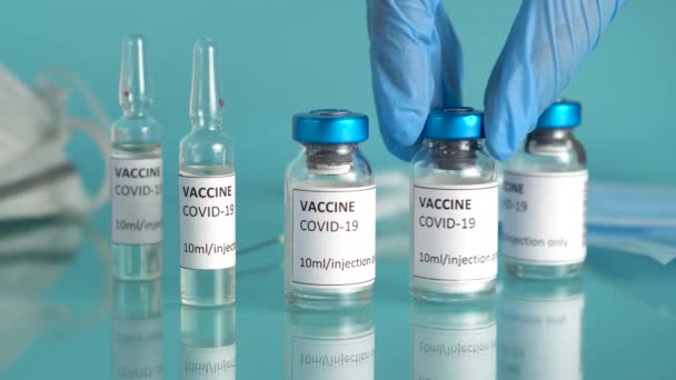 Covid-19 traitement d'immunisation. Médecins main prend flacon de vaccin pour la guérison du coronavirus. Vaccination contre le coronavirus avec flacons et ampoules de vaccin. — Video