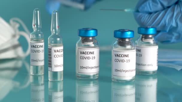 Aşı şişeleri ve ampullerle Coronavirus aşısı. Doktorlar ellerinde Coronavirus tedavisi için şırınga ve aşı şişesi tutuyor. Covid-19 aşısı araştırmacıların elinde. Salgın sırasında klinik deney. — Stok video