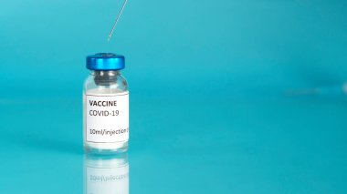 Coronavirus aşı şişesi. Aşı şişesiyle kapak aşısı. Mavi arka plan. Kopyalama alanı olan pankart.