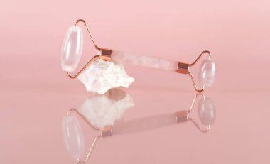 Yüz masajı için Gouache kuvars silindiri. Sağlıklı ve genç ciltler için yaşlanma ve kaldırma. Evde cilt bakımı. Pembe arka planda organik yüz kozmetikleri. Spa tedavileri.