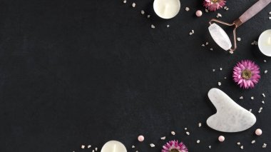 Gouache kazıyıcı ve yüz masajı silindirli spa tedavileri. Cilt bakımı moda. Gençlik teni için kaldırıyorum. Karanlık arka planda deniz tuzu ve mumlarla organik kozmetik ürünleri. Uzayı kopyala Üst görünüm.