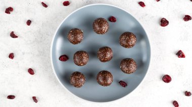 Mavi tabakta enerji topları. Ev yapımı çiğ vejetaryen fındık, hurma, fıstık ezmesi, kakao tozu, hindistan cevizi taneleri, yulaf ve kuru kızılcık. Sağlıklı beslenme. Spor atıştırmalığı. Seçici odak