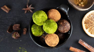 Süper yemek. Tarçınlı enerji topları, portakal dilimleri ve siyah çikolata parçaları. Ev yapımı çiğ vejetaryen tatlı, kibrit çay tozu ve kakao tozuyla kaplı. Sağlıklı beslenme. Seçici odaklanma. Üst görünüm.