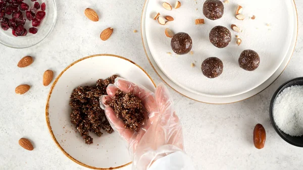 Step by step cooking Energy balls. Step 9 recipe of no bake energy balls. Making round balls from the mixture of nuts, dates, cocoa powder, coconut flakes, oats and dried cranberry. Healthy eating.