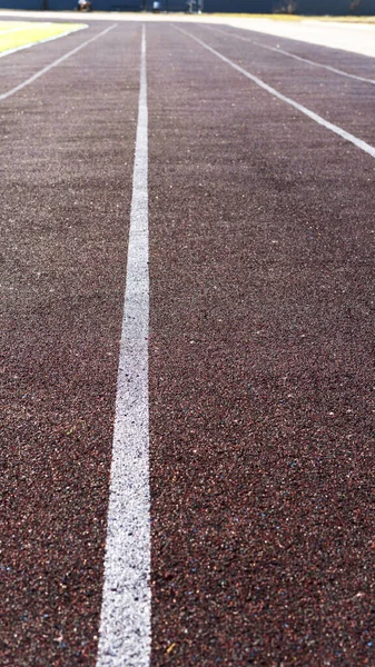 Běžet na sportovním stadionu. Červená běžecká nebo běžecká závodní guma s bílými liniemi a texturou. Prázdné pozadí běžící stopy. Selektivní zaměření. — Stock fotografie