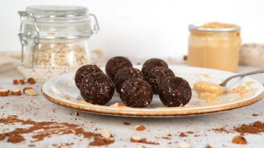 Süper yiyecek enerji topları. Beyaz tabakta, yulaf ezmesi ve fıstık ezmeli ev yapımı çiğ vegan tatlı. Sağlıklı beslenme. Spor atıştırmalığı. Seçici odak