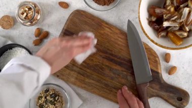 Woman cleaning wooden cutting board with cleaning cloth. Housekeeping concept. 