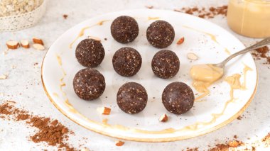 Süper yiyecek enerji topları. Beyaz tabakta, yulaf ezmesi ve fıstık ezmeli ev yapımı çiğ vegan tatlı. Sağlıklı beslenme. Spor atıştırmalığı. Seçici odak
