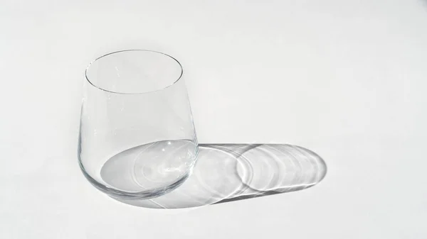 Empty clean glass on white background with sunlight and deep shadow of glass. Hard light. — Φωτογραφία Αρχείου