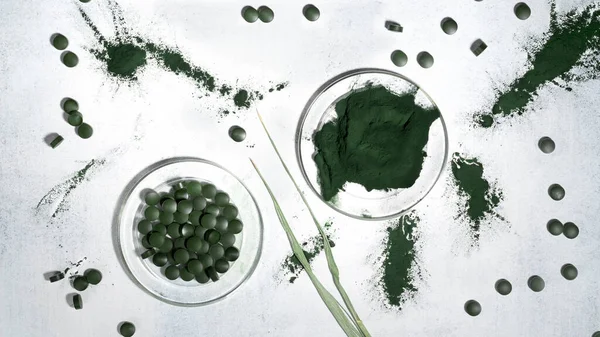 绿色螺旋藻海藻粉与螺旋藻片放在玻璃板上。超食物，健康饮食排毒的概念。顶部视图。平躺在床上. — 图库照片