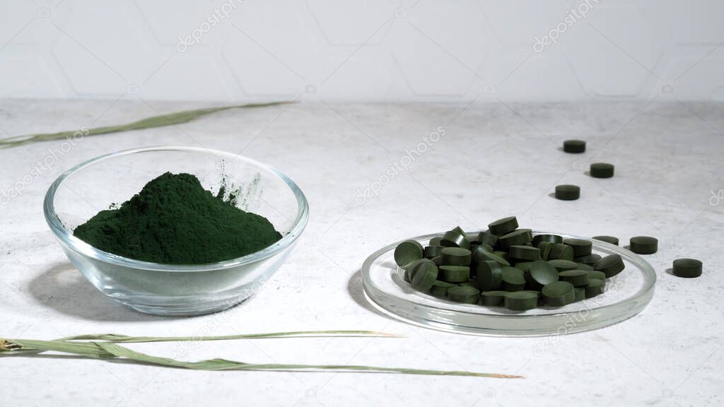 Green spirulina algae seaweed powder with spirulina chlorella pills on a glass bawl. Superfood, healthy eating detox concept. 