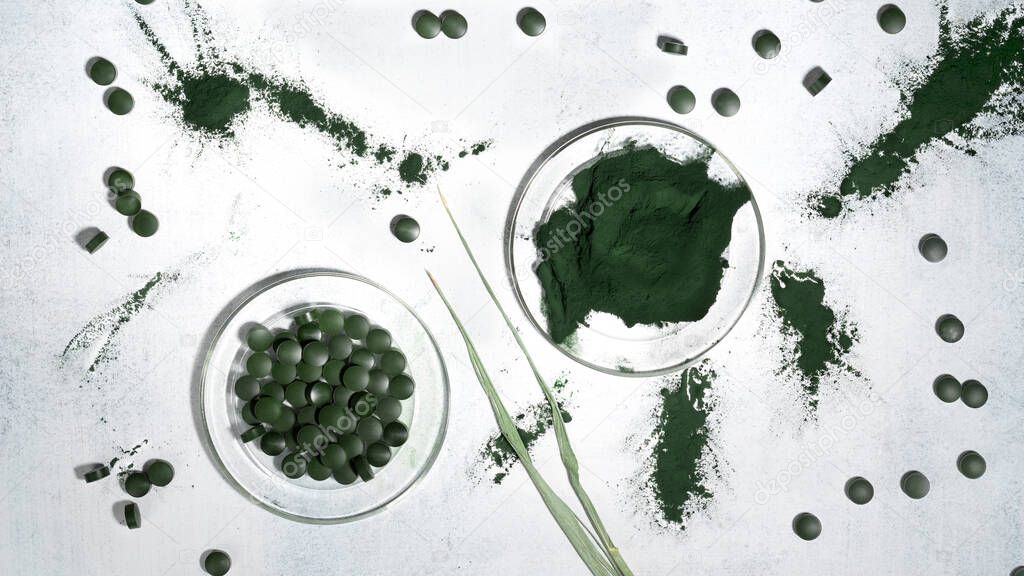 Green spirulina algae seaweed powder with spirulina chlorella pills on a glass plates. Superfood, healthy eating detox concept. Top view. Flat lay.