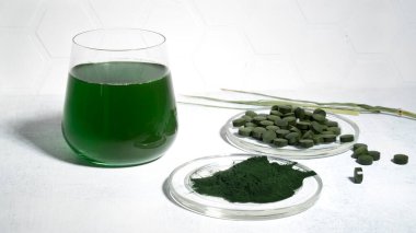 Etrafa saçılmış yeşil spirulina alg tozu ve spirulina içeceği ve spirulina klorella hapları. Süper yiyecek, detoks içeceği. Sağlıklı bakım konsepti. Yan görüş. Yatay yönelim.