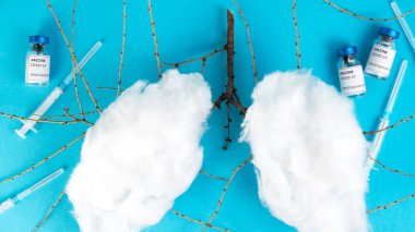 Kapak aşısı konsepti. Coronavirus Covid-19 aşı tüpleri, şırıngalar ve akciğer şeklinde pamuk. Mavi tıbbi geçmiş.