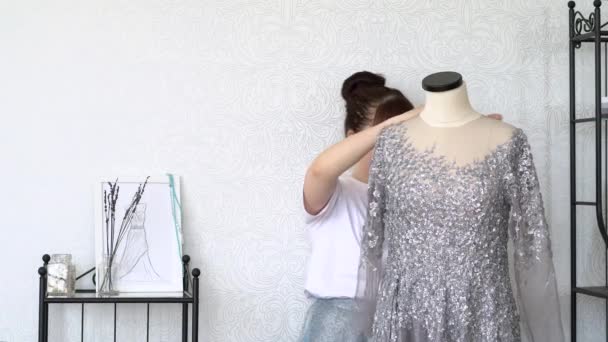 Ung modedesigner sätter en klänning på en sömnad skyltdocka eller docka. Genomsnittsplan — Stockvideo