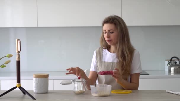 Food video blogger přidává maliny do sklenice, dělá video pomocí telefonu. — Stock video