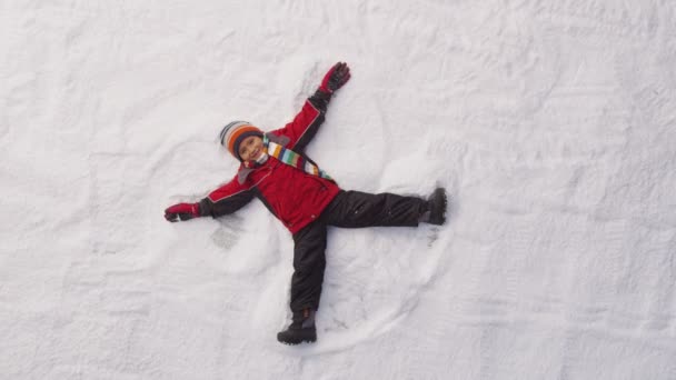 Menino fazendo um anjo da neve — Vídeo de Stock