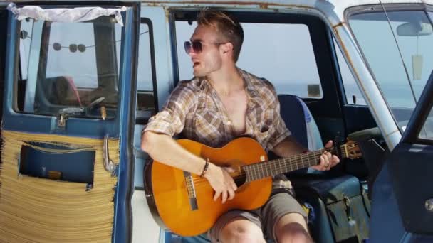 Парень играет на гитаре в фургоне — стоковое видео