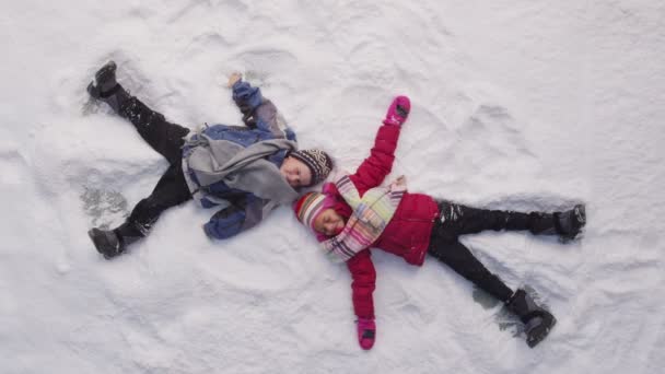 Niños haciendo ángeles de nieve — Vídeos de Stock